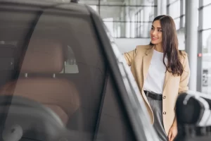 Young woman looking at a new car in the dealership showroom before considering finance and trade in options