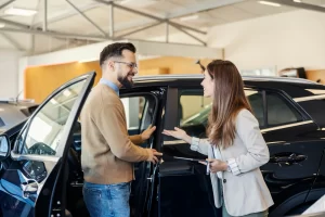 A car dealer is helping the man learn about features of a new car he's thinking of buying