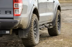 Site view of muddy grey Ford Ranger parked on level dirt.